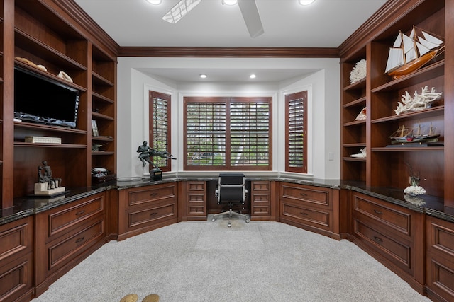 carpeted office space featuring crown molding, built in desk, and ceiling fan