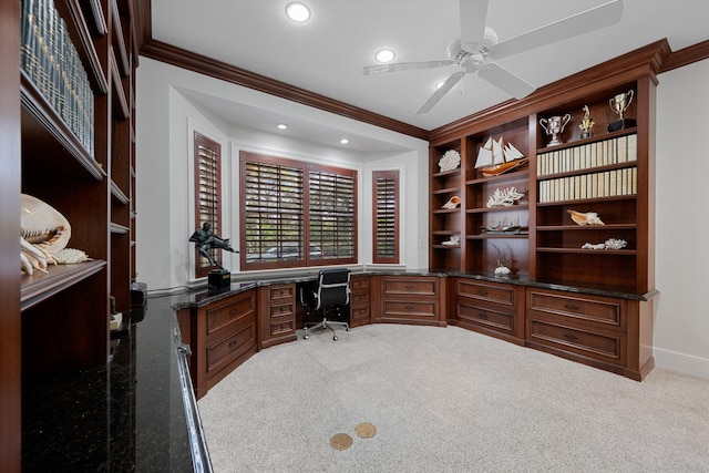 home office with ceiling fan, light colored carpet, ornamental molding, and built in desk