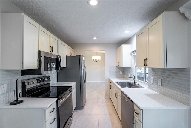 kitchen featuring appliances with stainless steel finishes, light tile patterned floors, a textured ceiling, white cabinets, and sink