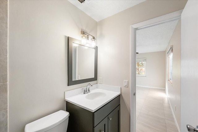 bathroom featuring toilet, a textured ceiling, tile patterned floors, and vanity