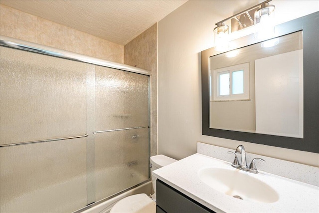 full bathroom featuring shower / bath combination with glass door, a textured ceiling, toilet, and vanity