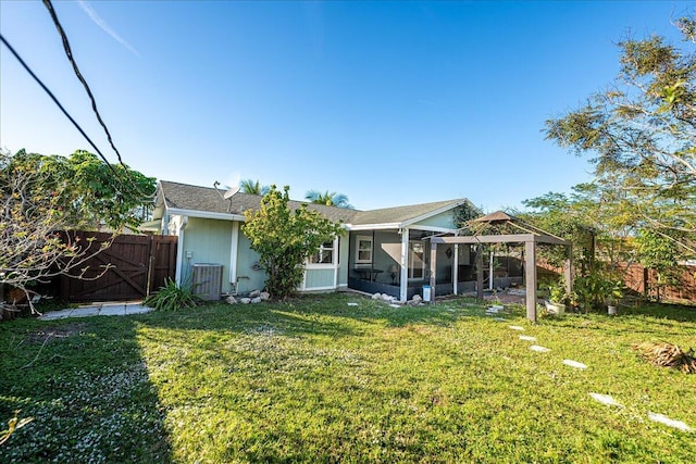 back of property with a lawn, a gazebo, central AC unit, and a sunroom