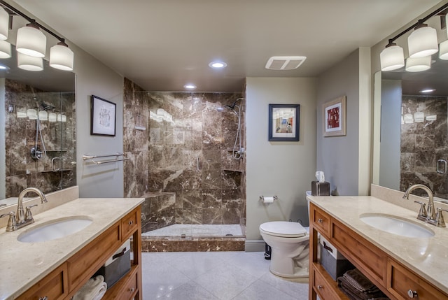 bathroom featuring toilet, tile patterned flooring, a tile shower, and vanity