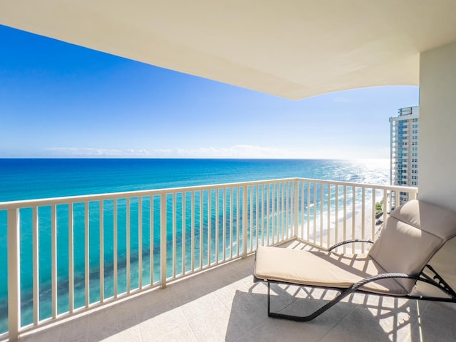 balcony featuring a view of the beach and a water view