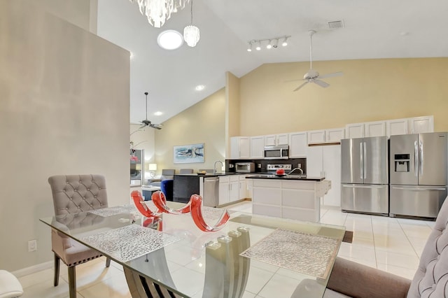 dining space featuring ceiling fan with notable chandelier, high vaulted ceiling, light tile patterned floors, and sink