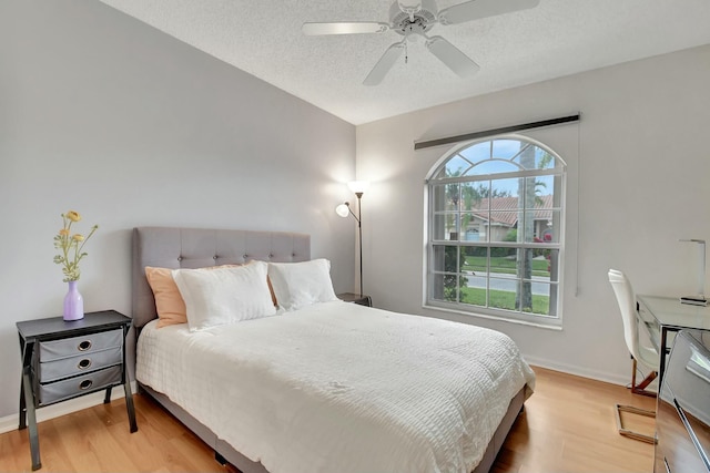 bedroom featuring light wood-type flooring, ceiling fan, and a textured ceiling