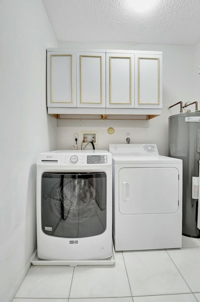 washroom with cabinets, washer and clothes dryer, electric water heater, and light tile patterned floors