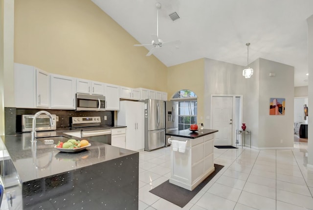 kitchen featuring hanging light fixtures, stainless steel appliances, light tile patterned floors, high vaulted ceiling, and white cabinetry