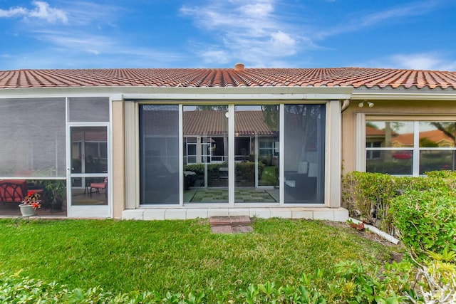 back of property with a lawn and a sunroom