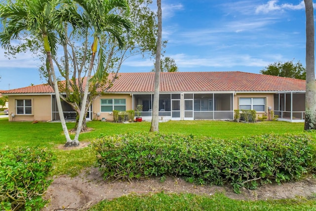 rear view of property featuring a yard and a sunroom