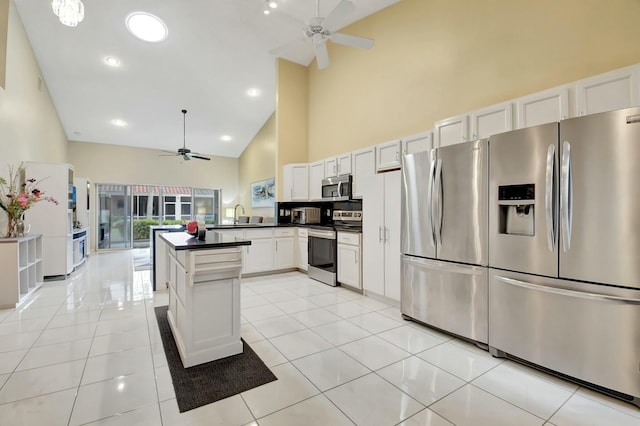 kitchen with appliances with stainless steel finishes, white cabinetry, light tile patterned flooring, and high vaulted ceiling