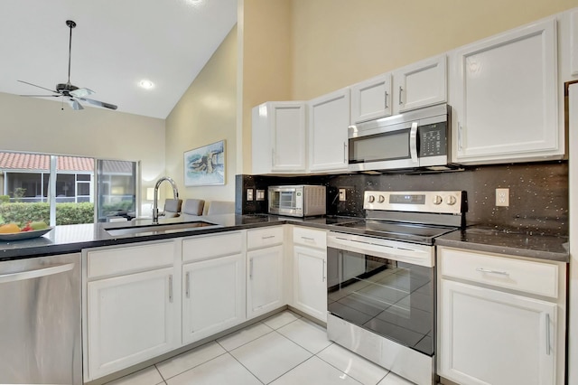 kitchen with appliances with stainless steel finishes, white cabinets, high vaulted ceiling, and sink