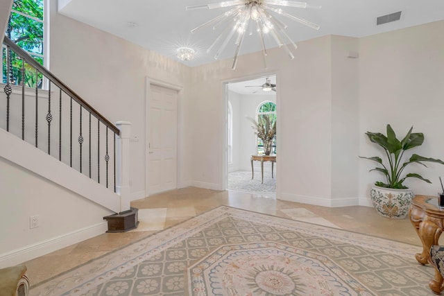 entrance foyer with ceiling fan with notable chandelier