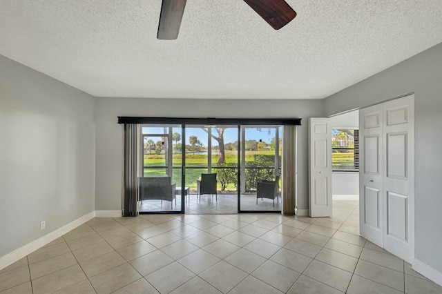 empty room featuring light tile patterned flooring, a textured ceiling, and ceiling fan