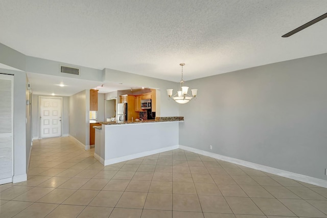 interior space featuring a textured ceiling, ceiling fan with notable chandelier, and light tile patterned floors