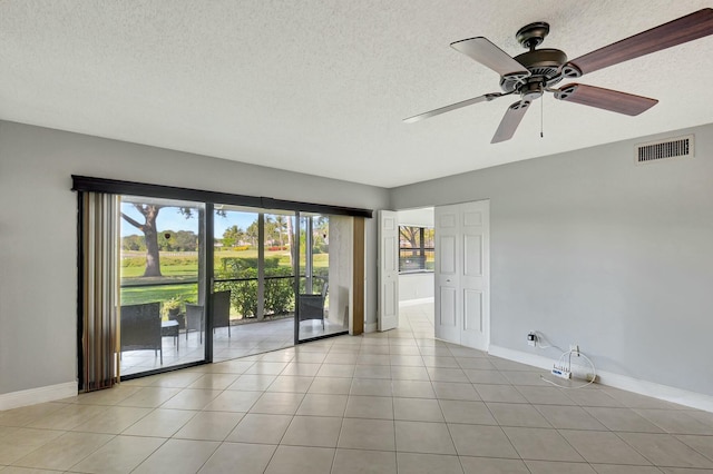 tiled empty room featuring ceiling fan and a textured ceiling