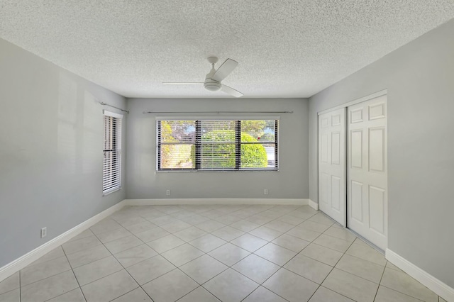 unfurnished bedroom featuring ceiling fan, a closet, light tile patterned flooring, and a textured ceiling