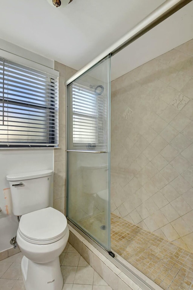 bathroom with toilet, tile patterned flooring, and a shower with door