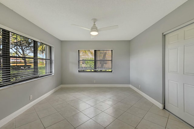 tiled empty room with ceiling fan and a textured ceiling