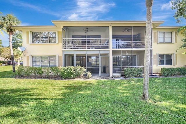 rear view of property with ceiling fan and a yard