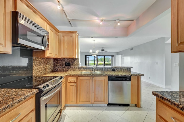 kitchen with sink, stainless steel appliances, dark stone countertops, and ceiling fan