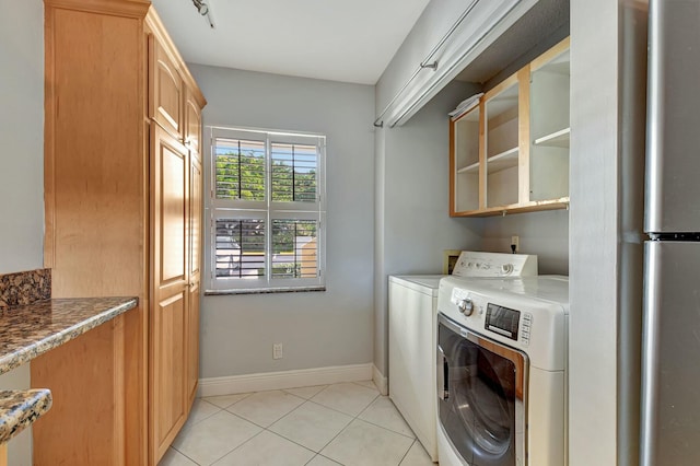 laundry area with washing machine and clothes dryer and light tile patterned floors