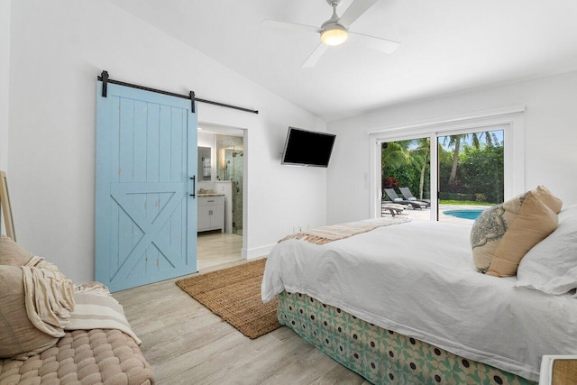 bedroom with connected bathroom, vaulted ceiling, access to outside, ceiling fan, and a barn door