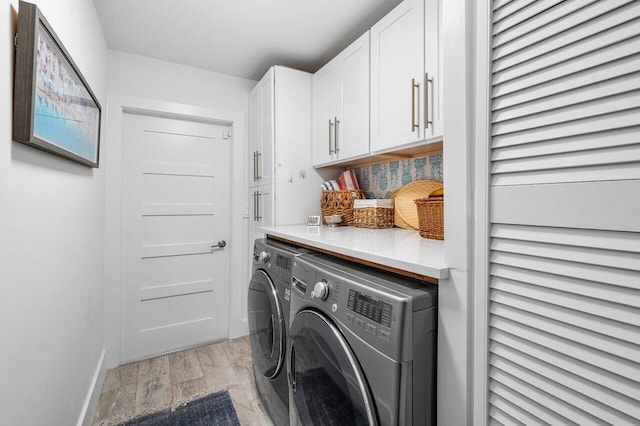 laundry area with cabinets, washing machine and clothes dryer, and light hardwood / wood-style floors