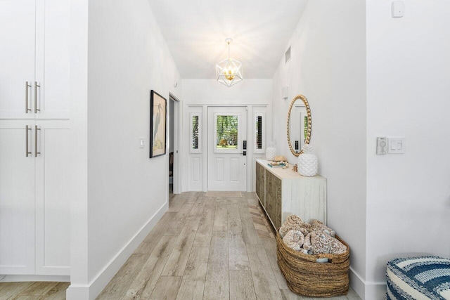 hallway with an inviting chandelier and light wood-type flooring