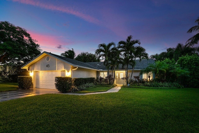 single story home featuring a garage and a lawn