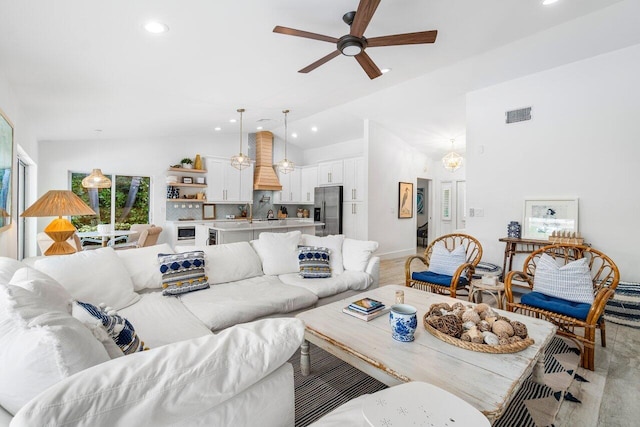 living room featuring ceiling fan with notable chandelier and vaulted ceiling