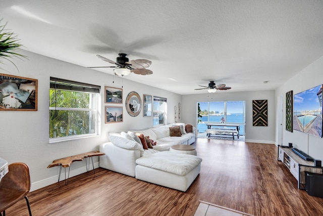 living room with ceiling fan, wood-type flooring, and a textured ceiling