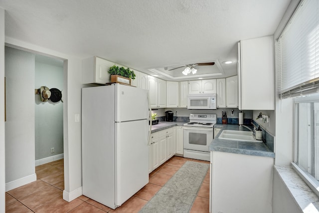 kitchen with light tile patterned floors, sink, white appliances, and white cabinets