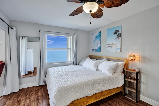 bedroom featuring dark wood-type flooring, ceiling fan, and a water view