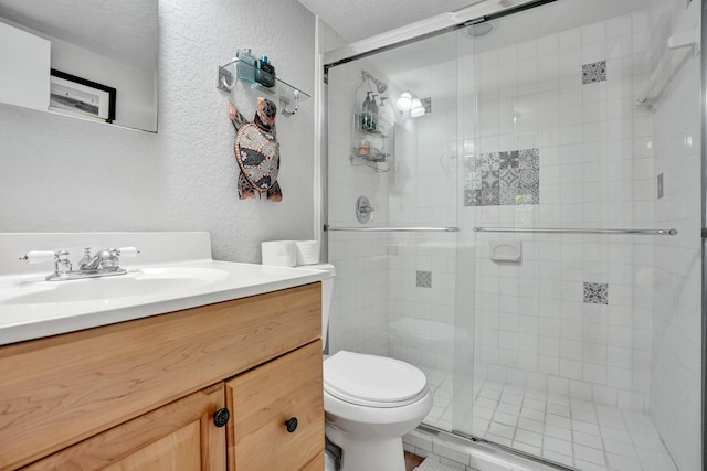 bathroom featuring a textured ceiling, toilet, vanity, and an enclosed shower