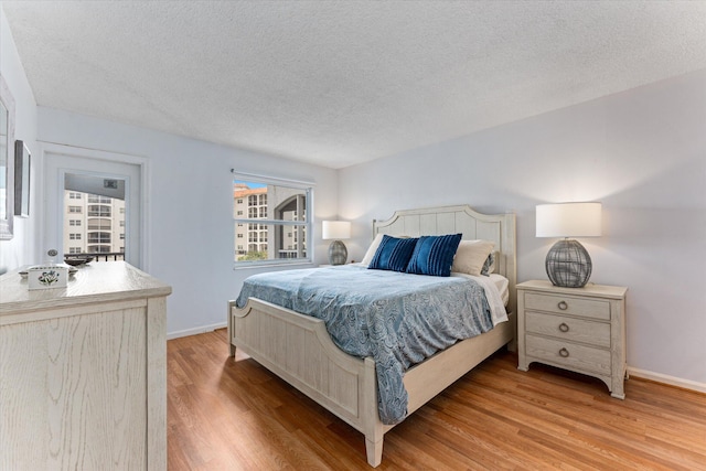 bedroom featuring a textured ceiling and light hardwood / wood-style flooring