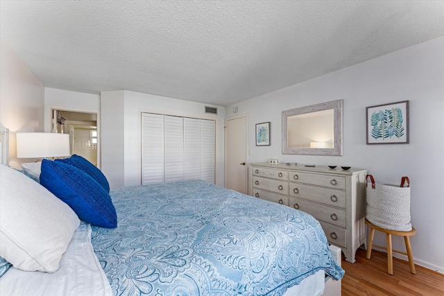 bedroom with a textured ceiling, a closet, and hardwood / wood-style floors