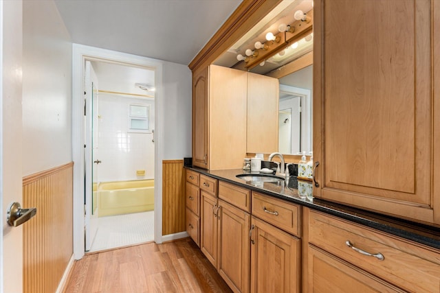 bathroom with vanity, wood walls, hardwood / wood-style flooring, and washtub / shower combination