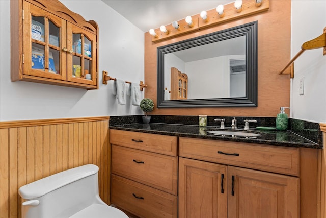 bathroom with toilet, wooden walls, and vanity