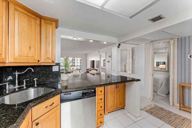 kitchen with sink, light tile patterned floors, stainless steel dishwasher, backsplash, and dark stone counters