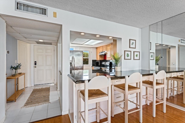 kitchen with appliances with stainless steel finishes, hanging light fixtures, kitchen peninsula, a kitchen bar, and backsplash