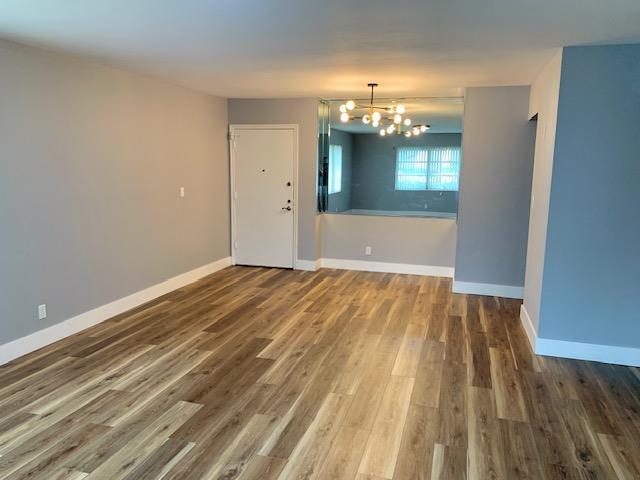 spare room with an inviting chandelier and wood-type flooring