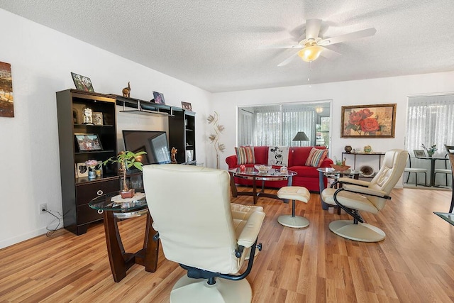 living room with a textured ceiling, ceiling fan, and hardwood / wood-style flooring