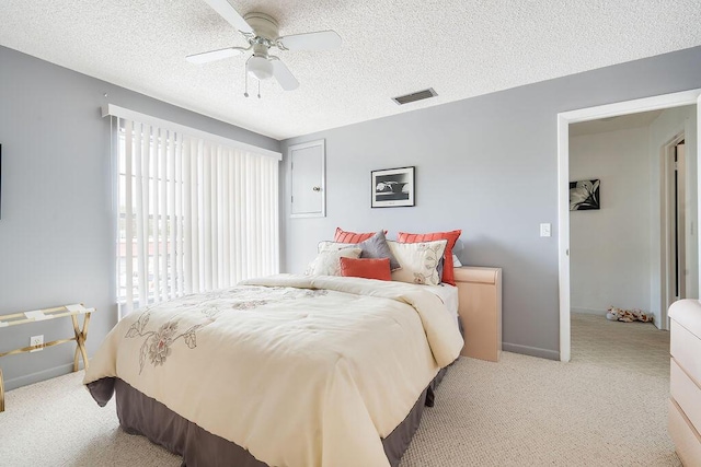 carpeted bedroom featuring ceiling fan and a textured ceiling