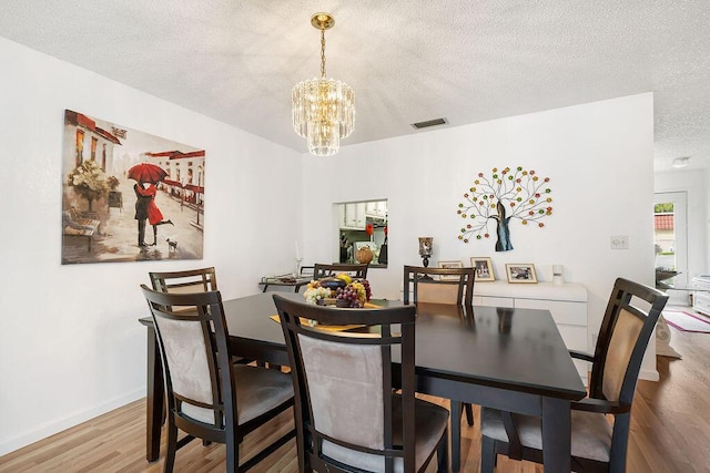 dining area featuring a textured ceiling, an inviting chandelier, and hardwood / wood-style floors