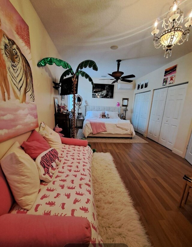 bedroom featuring ceiling fan with notable chandelier, wood-type flooring, and a wall mounted air conditioner