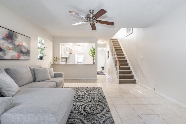 living room featuring ceiling fan, a textured ceiling, and light tile patterned floors