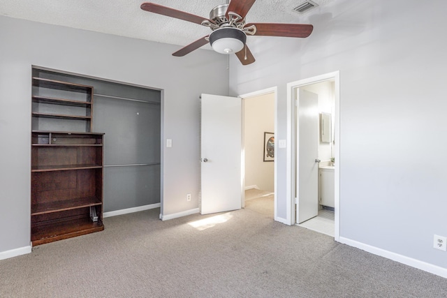 unfurnished bedroom with a textured ceiling, light carpet, connected bathroom, ceiling fan, and a closet