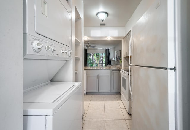 laundry area featuring stacked washer and clothes dryer, ceiling fan, and light tile patterned flooring