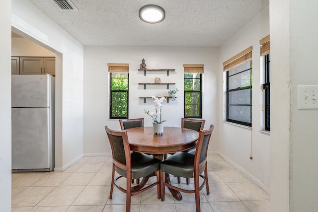 dining area featuring a textured ceiling and light tile patterned floors